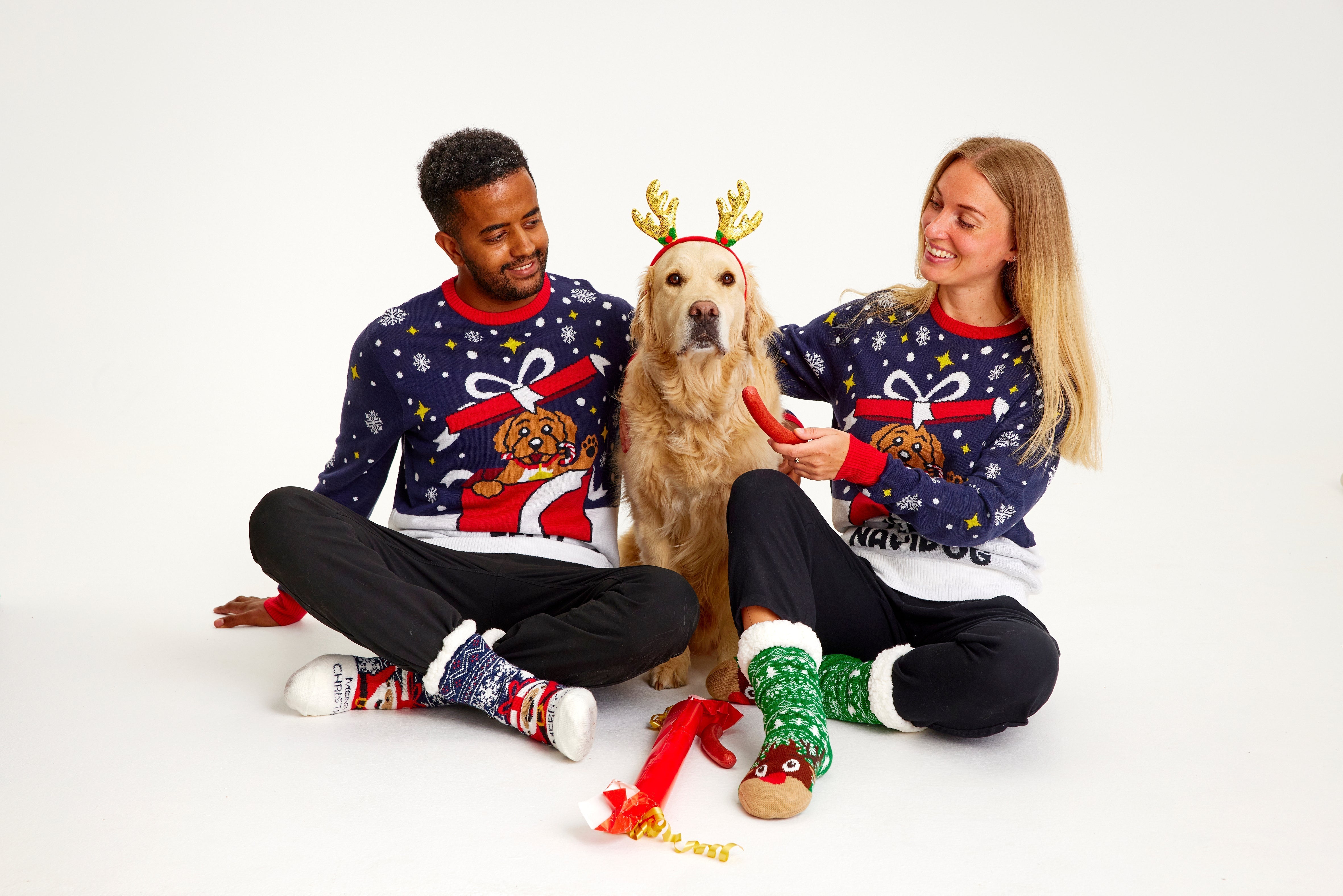 Ein Paar mit Hund, das einen blau-weißen Weihnachtspulli mit einem Hund trägt.